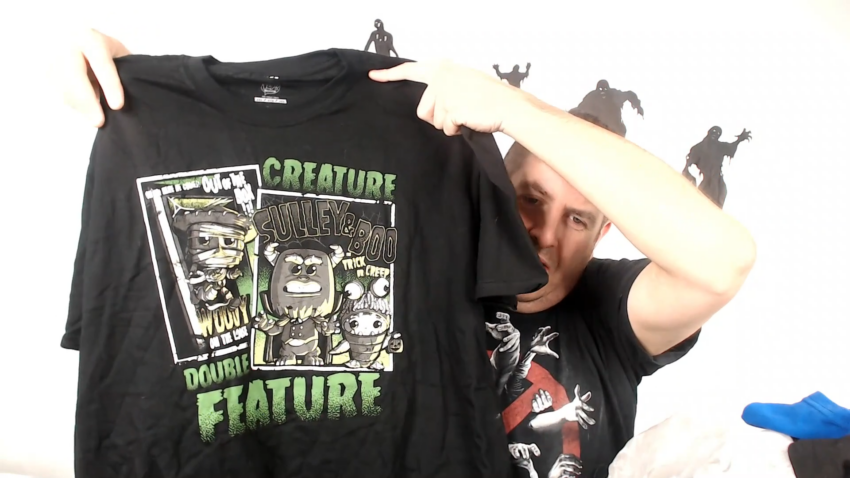 A Person Holding up A Black T-Shirt, Promoting Video Game-Related Merchandise