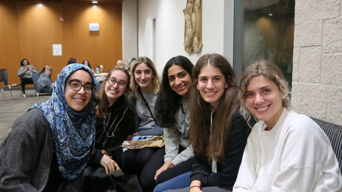A group of smiling students sitting together indoors, representing classmates from a Middle Eastern Cultures elective