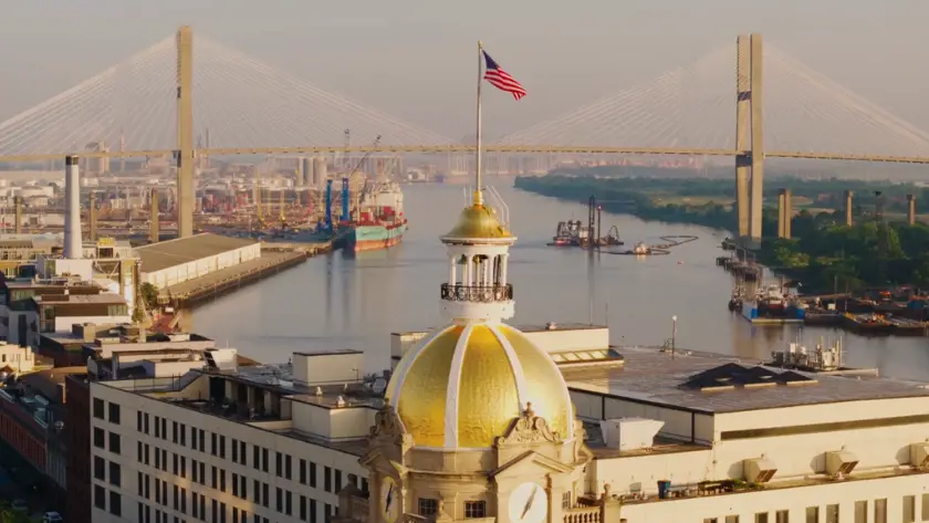 A view of Savannah’s gold-domed city hall with the river and bridge in the background