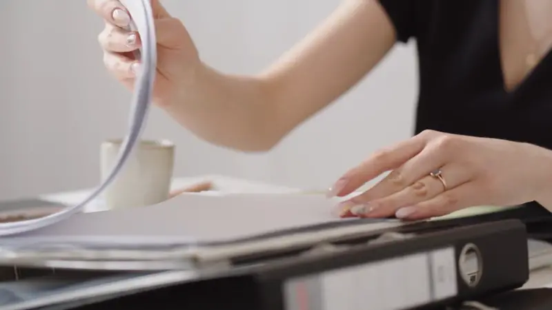 A person reviews documents in a binder for incident reporting and risk assessments