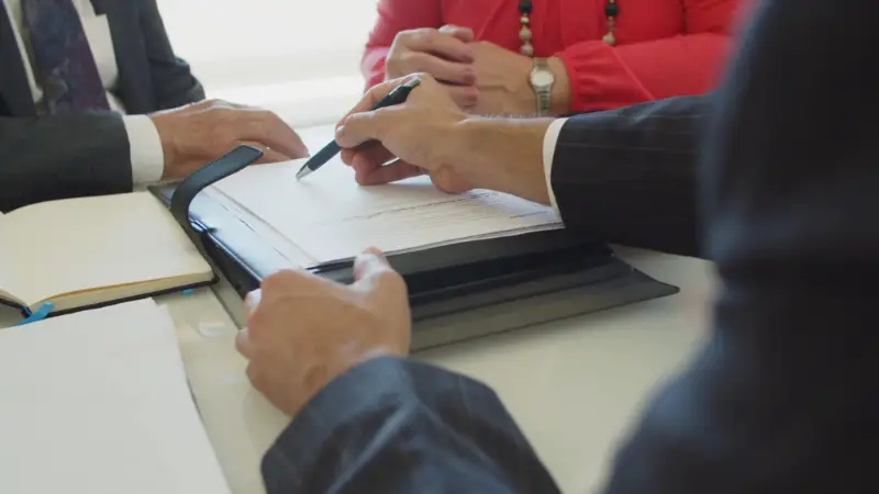 Business professionals review compliance paperwork during a meeting