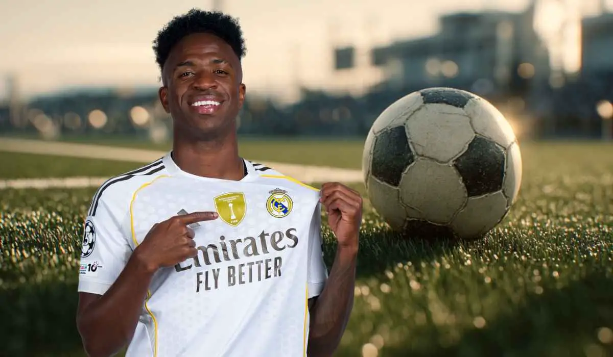 Smiling soccer player pointing at his jersey badge with a ball on the field behind him