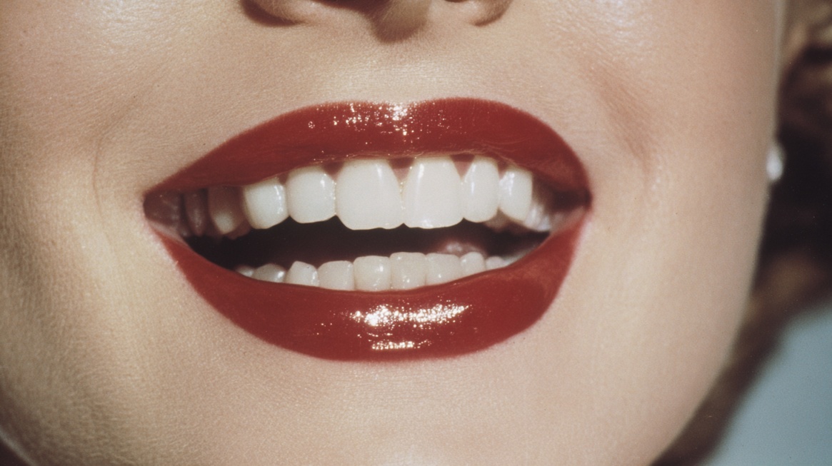 Close up of a bright white smile with glossy red lipstick