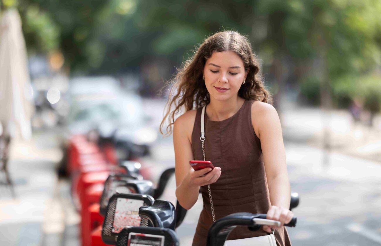 Woman using a smartphone next to a bike share station