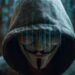 Person in a hoodie wearing a mask with digital code overlay representing online anonymity