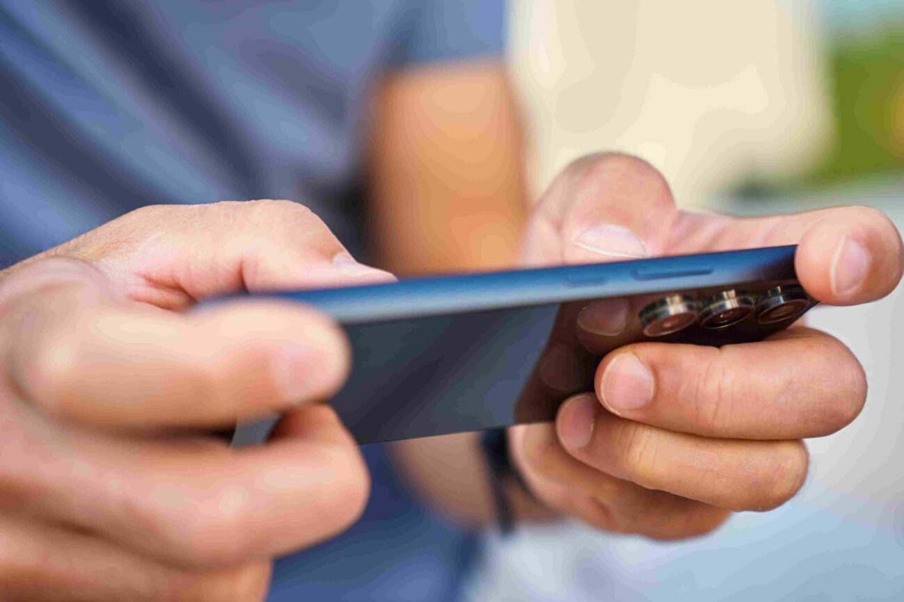 Close-up of a person holding and using a modern smartphone with multiple rear cameras