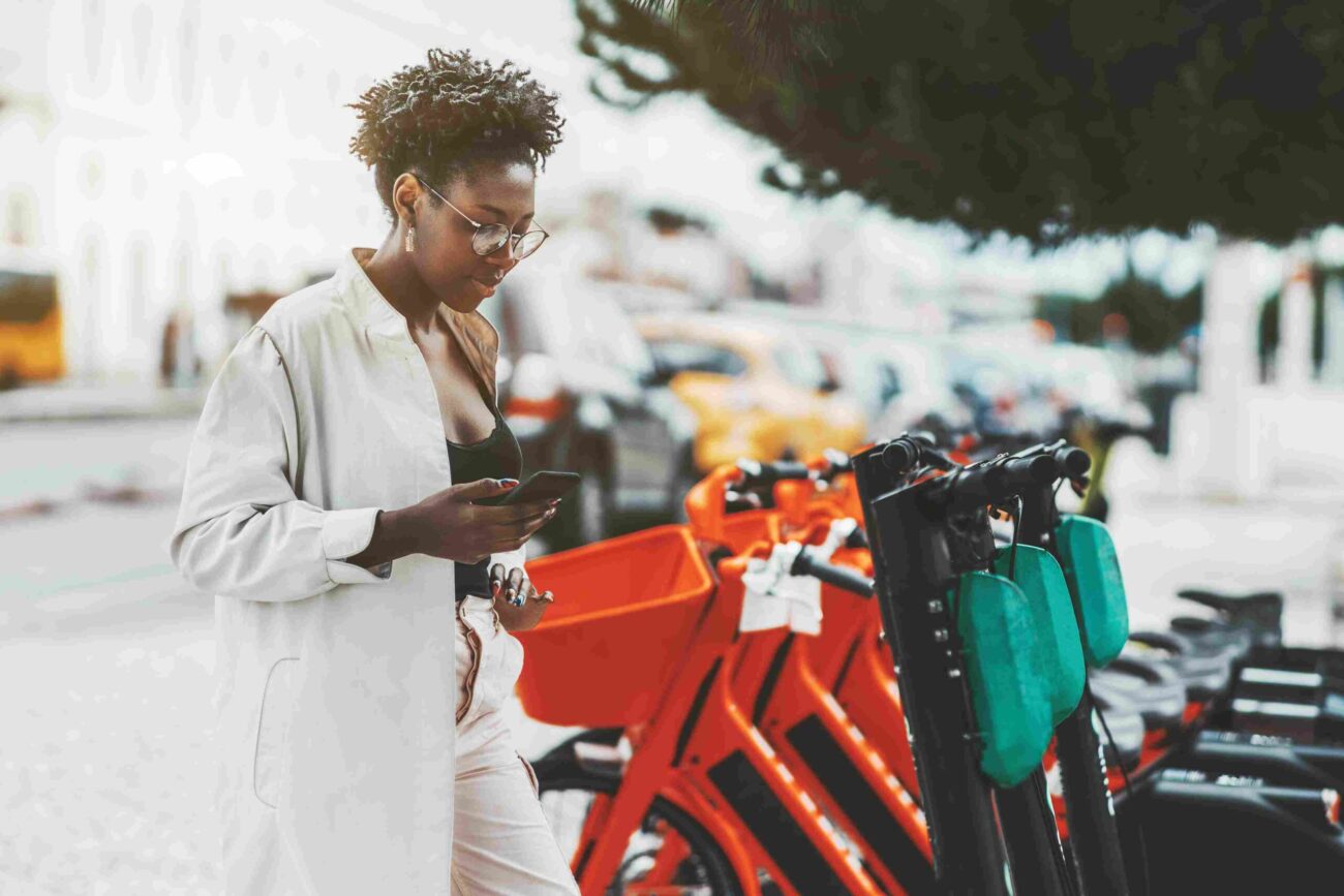 Woman using a smartphone next to shared e bikes in a city