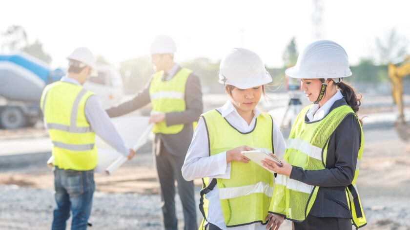 Construction crew members review project details on a tablet at an active jobsite