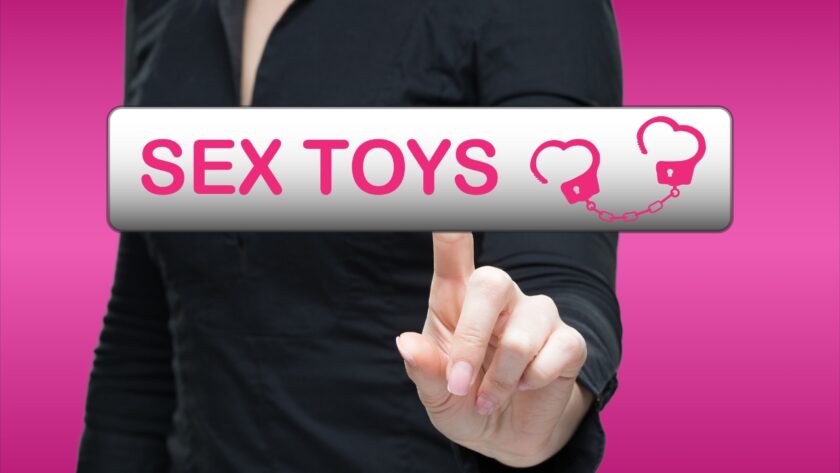 Person pressing a sex toys button on a pink screen