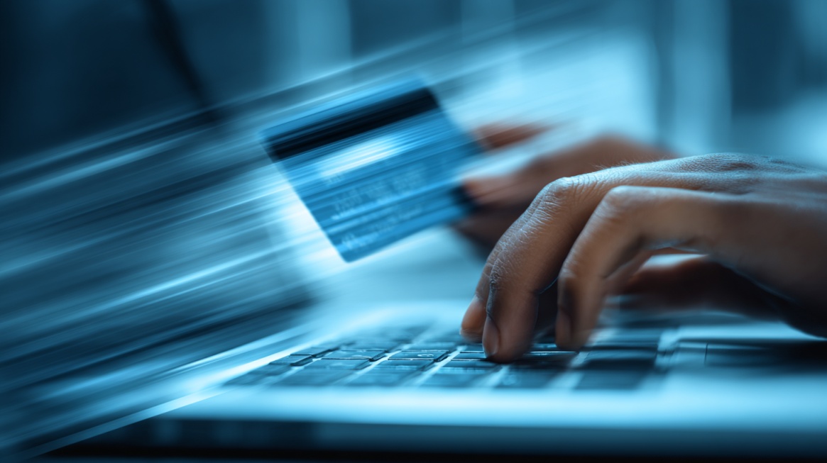 Close-up of hands typing on a laptop while holding a payment card, symbolizing fast online transactions and digital payments