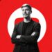 Man in a black jacket standing with crossed arms against a red YouTube-inspired background.