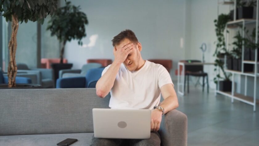 A worried man reacts to a casino loss on his laptop