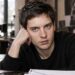 Tobey Maguire in a casual black sweater, seated in a film studio.