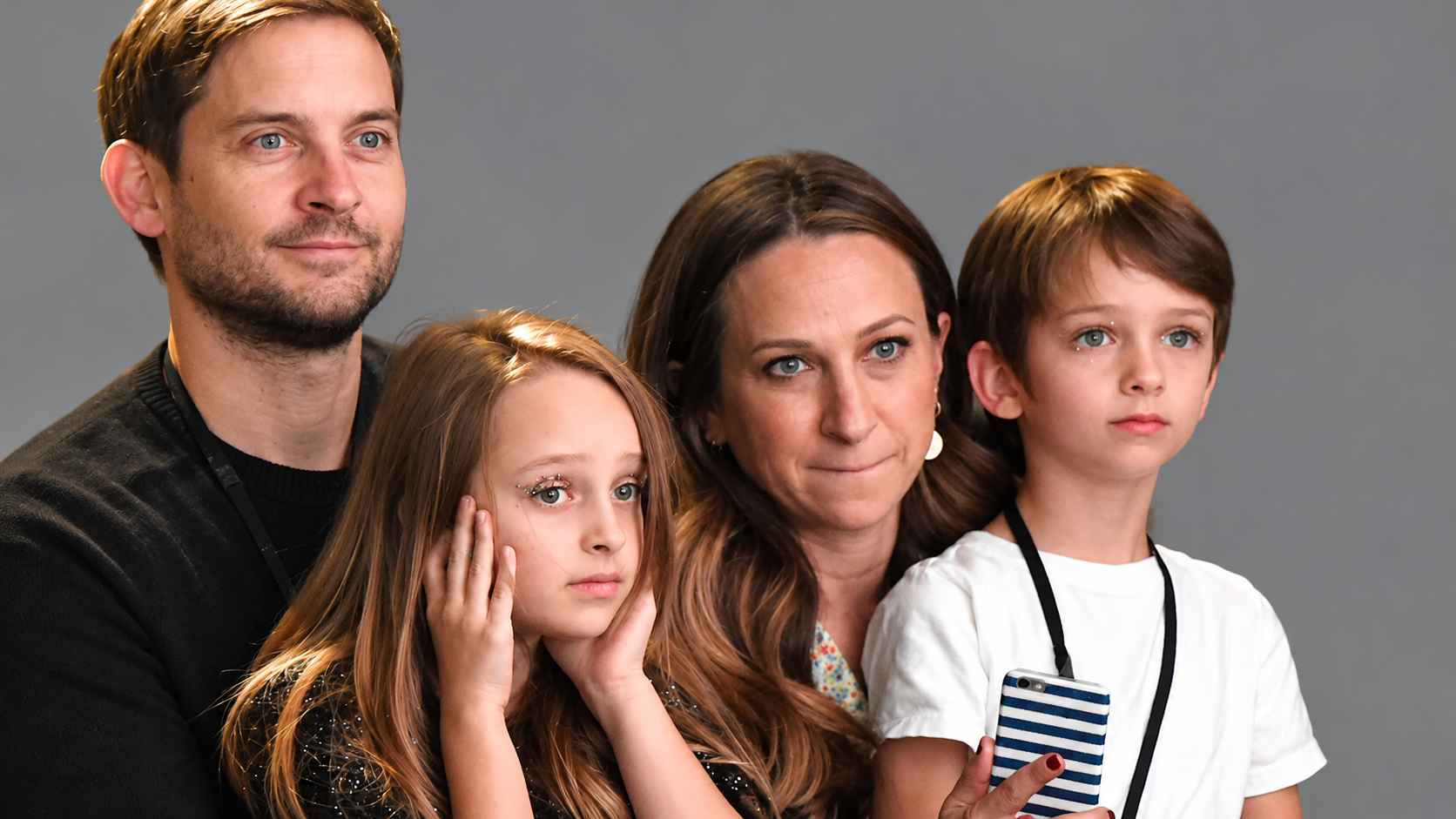 Tobey Maguire with Jennifer Meyer and their children, Ruby and Otis, against a grey background.